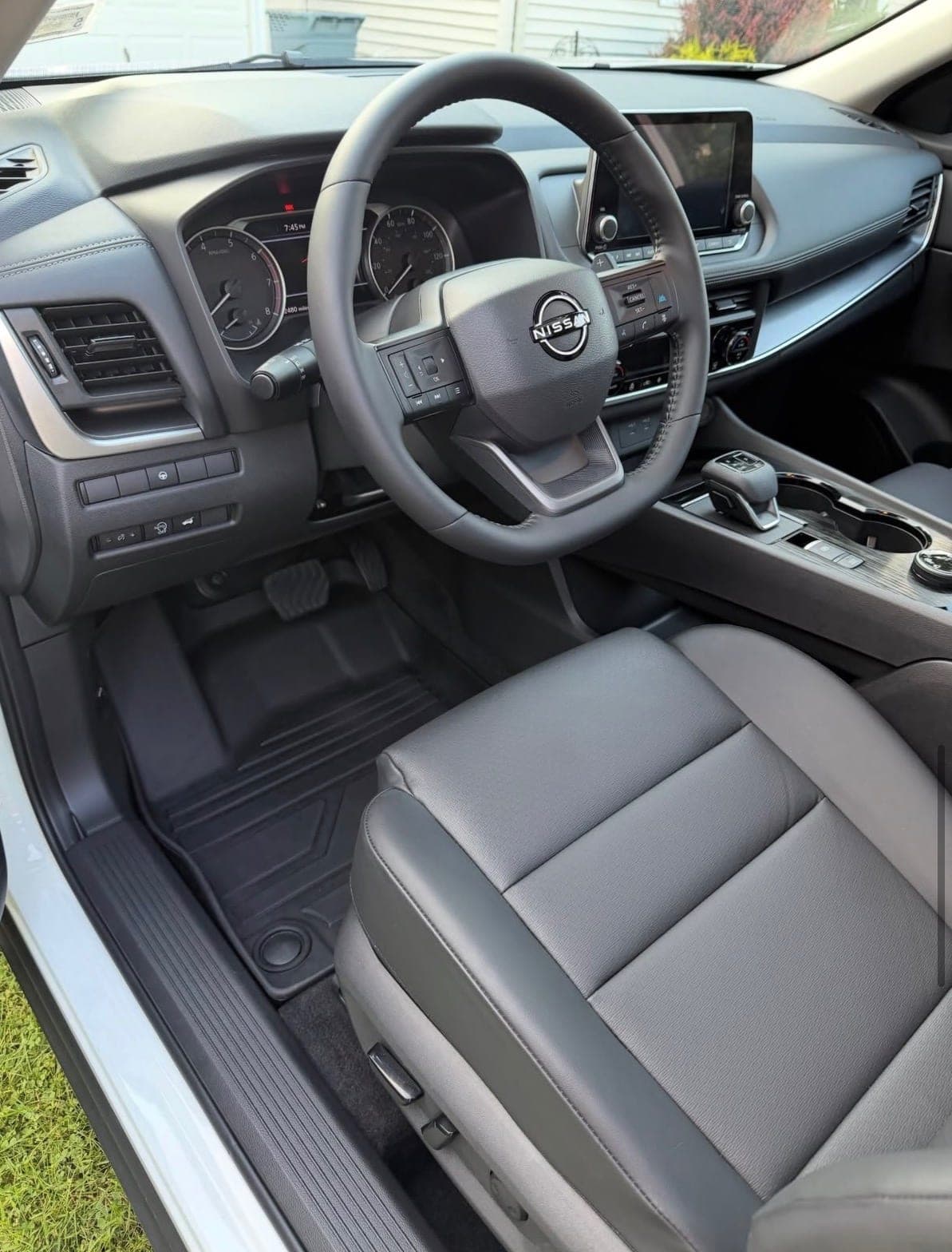 The driver's area of a Nissan after a full interior detail — clean dashboard, steering wheel, seat and floor mat