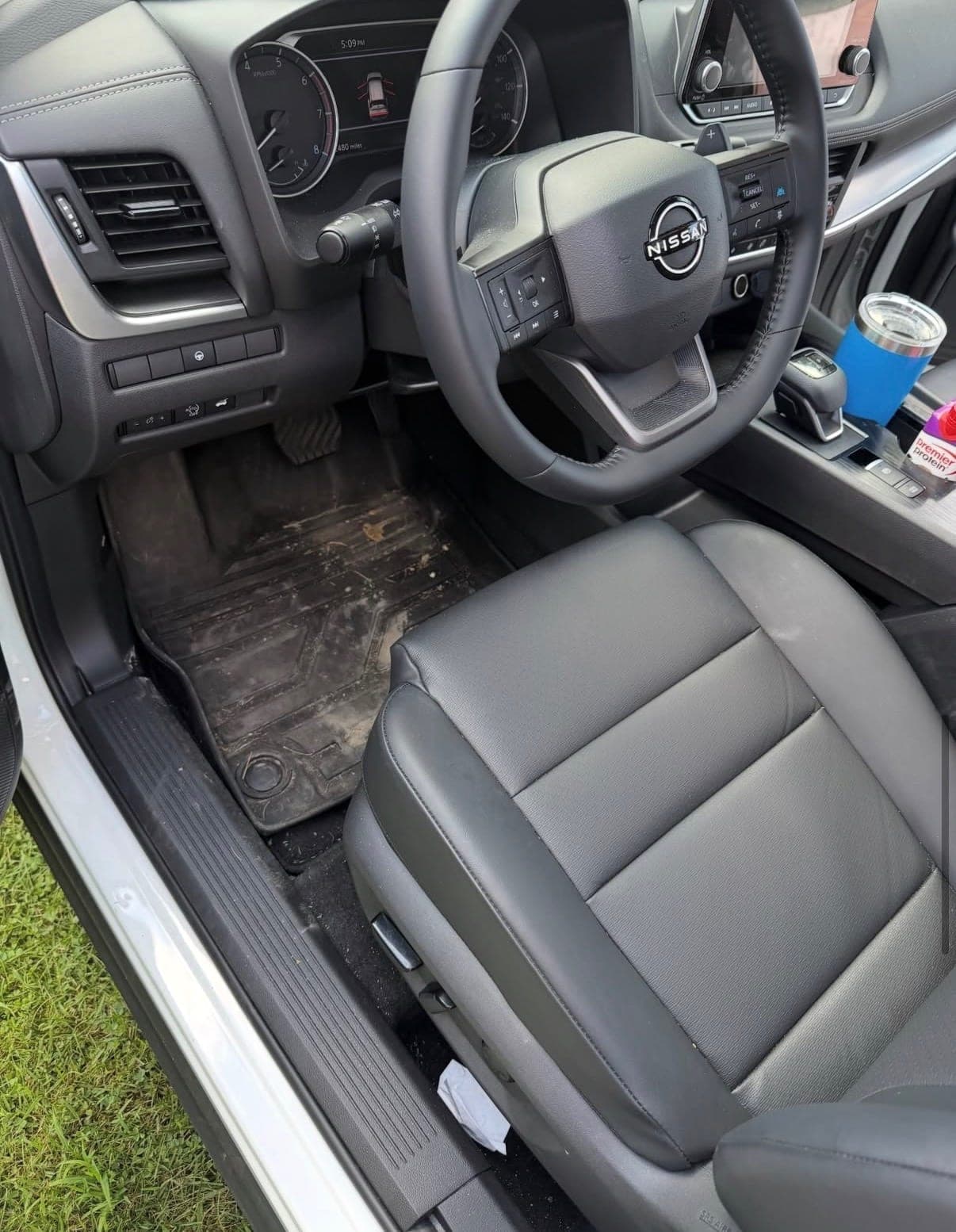 A driver's seat and footwell before detailing, with dirt and debris ground into the floor mat